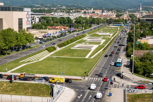 A bustling intersection in Zagreb, Croatia, showing city traffic against a green park backdrop.