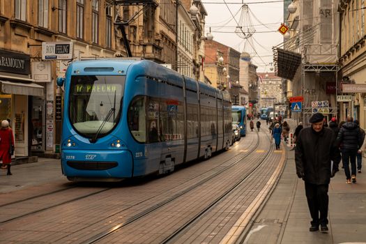 A blue tram travels through a bustling street in Zagreb, Croatia's capital city.