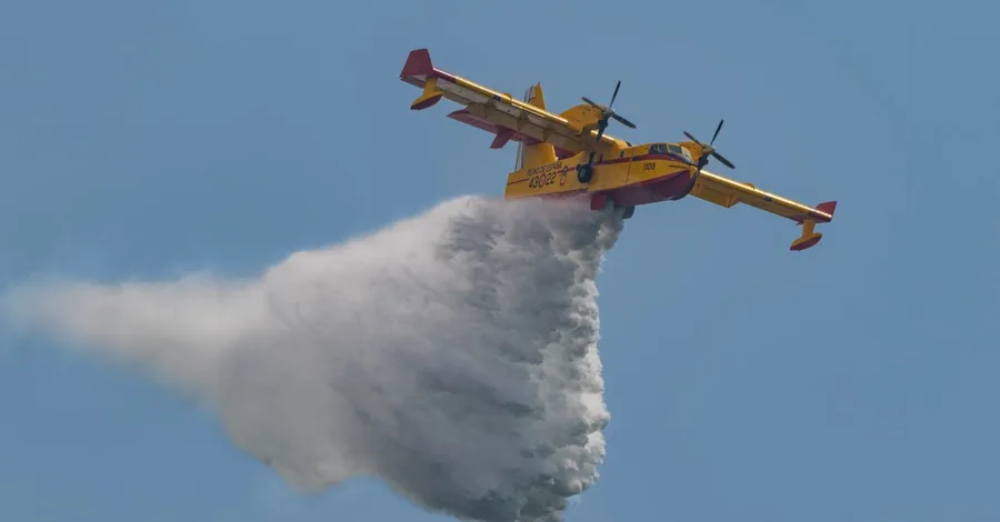 Aerial view of a firefighting plane deploying water over a fire in an emergency response.