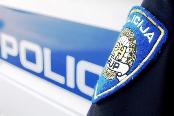 Oznaka hrvatske policije na uniformi ispred službenog policijskog vozila